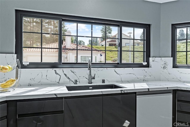kitchen featuring a sink, decorative backsplash, and dark cabinetry