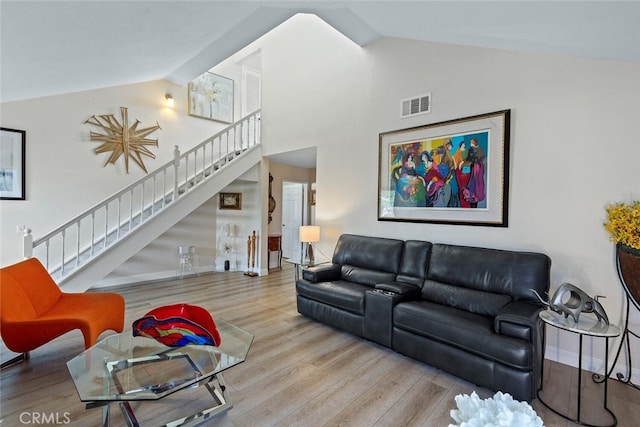 living room featuring visible vents, wood finished floors, stairway, high vaulted ceiling, and baseboards