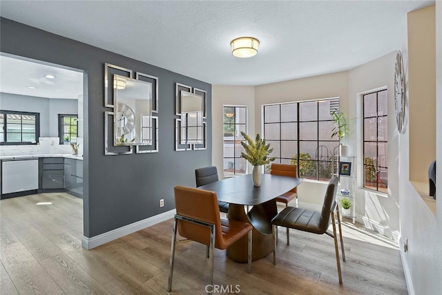 dining area with baseboards and light wood finished floors