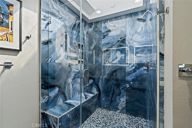 full bathroom featuring a marble finish shower and a textured wall