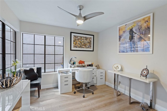 office featuring a ceiling fan, baseboards, and light wood-style flooring