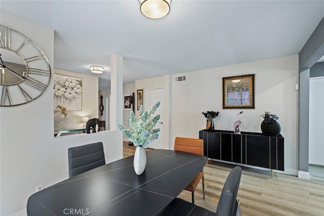 dining area featuring baseboards, visible vents, and wood finished floors