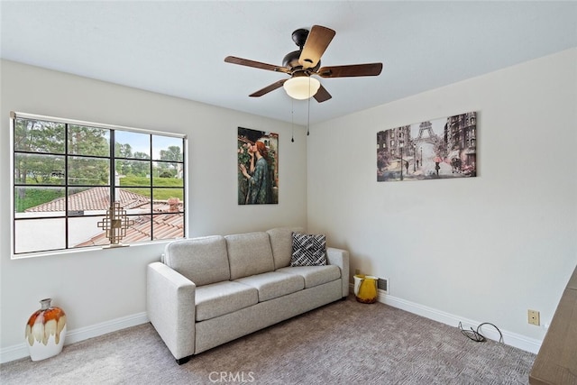 living area with baseboards, ceiling fan, and carpet