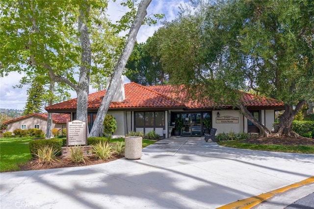 mediterranean / spanish-style house with a tiled roof, concrete driveway, and stucco siding