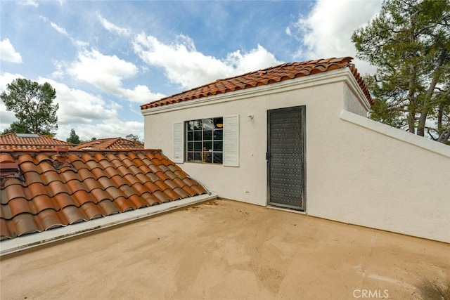 exterior space featuring a tiled roof, a patio, and stucco siding