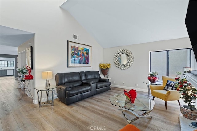 living room with visible vents, baseboards, wood finished floors, and high vaulted ceiling