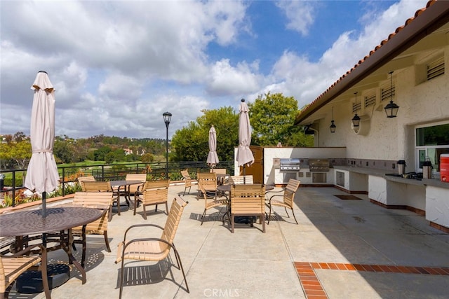 view of patio with fence, outdoor dining space, exterior kitchen, and area for grilling