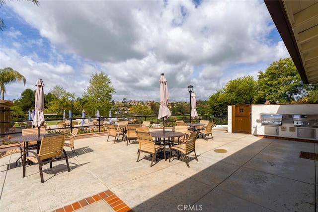 view of patio / terrace with exterior kitchen, outdoor dining area, and a grill