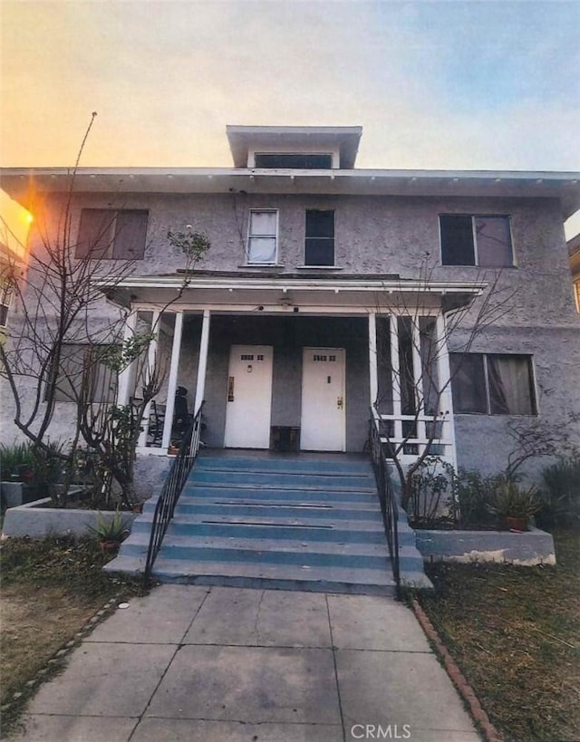 view of front of home with covered porch, driveway, and stucco siding