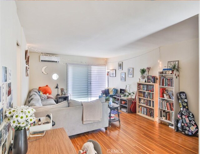 living area with a wall unit AC and wood finished floors