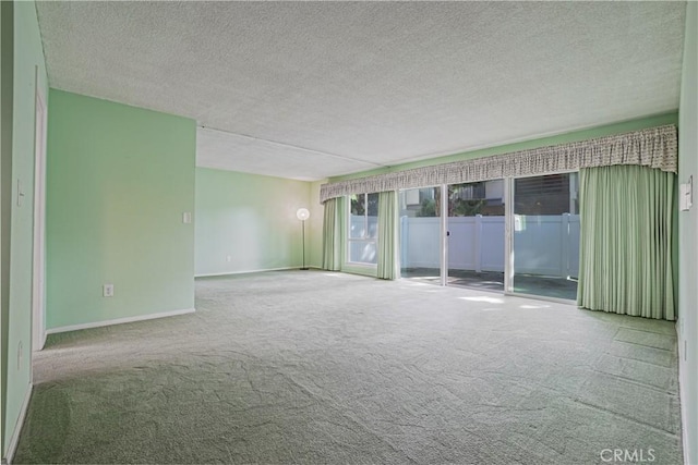 spare room with a textured ceiling, baseboards, and carpet floors