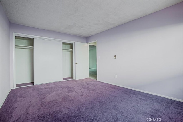 unfurnished bedroom featuring a closet, carpet flooring, a textured ceiling, and baseboards