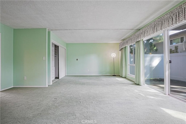 carpeted spare room featuring baseboards and a textured ceiling