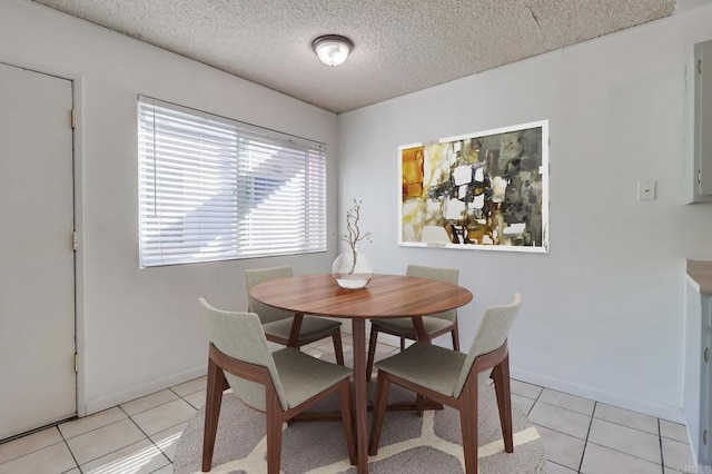 dining space with light tile patterned floors, baseboards, and a textured ceiling