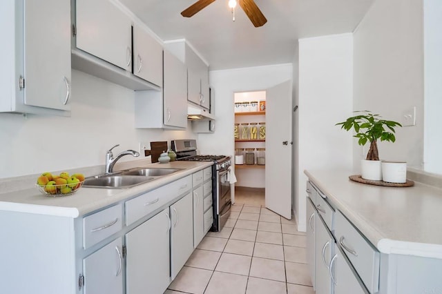 kitchen featuring ceiling fan, under cabinet range hood, light countertops, gas stove, and a sink