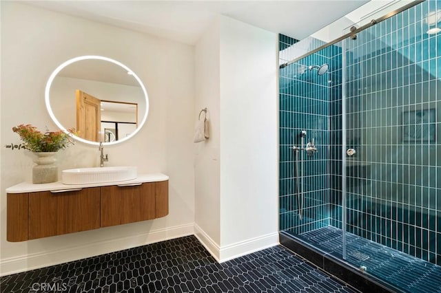 full bathroom with a tile shower, tile patterned flooring, vanity, and baseboards