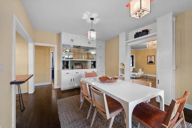 dining space featuring dark wood finished floors, baseboards, and a chandelier