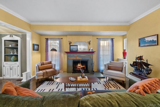 living room featuring baseboards, wood finished floors, a fireplace with flush hearth, and crown molding