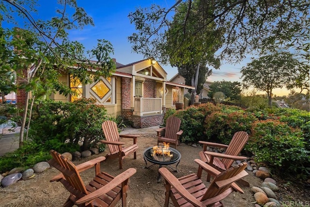back of house with an outdoor fire pit and brick siding