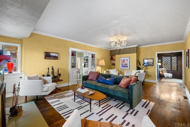 living area with ornamental molding, a notable chandelier, wood finished floors, and baseboards