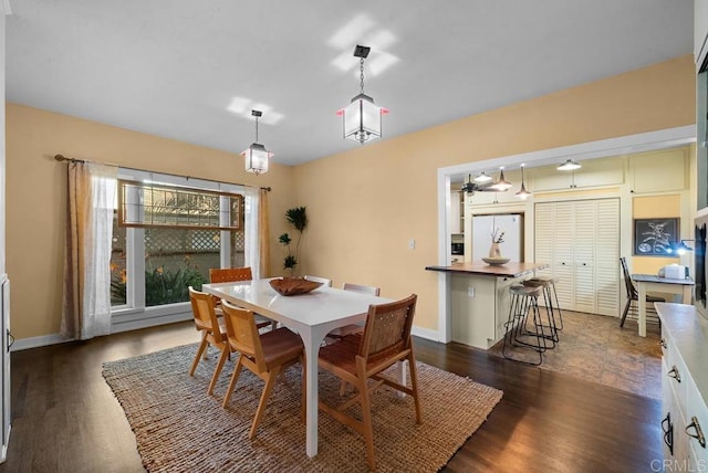 dining room featuring dark wood finished floors, baseboards, and a ceiling fan