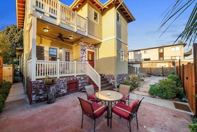 view of patio featuring a fenced backyard, covered porch, a ceiling fan, outdoor dining space, and a balcony