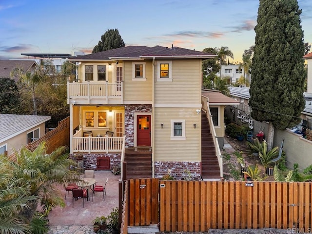 view of front of house with a balcony, a gate, a patio area, stairway, and a fenced front yard