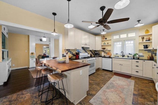 kitchen featuring a kitchen breakfast bar, open shelves, a sink, under cabinet range hood, and white appliances