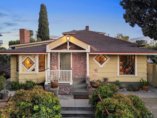 view of front of property with a chimney and roof with shingles