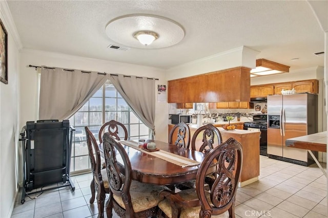 dining space featuring light tile patterned floors, visible vents, a textured ceiling, and crown molding