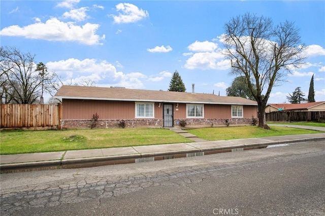 ranch-style home with a front lawn and fence