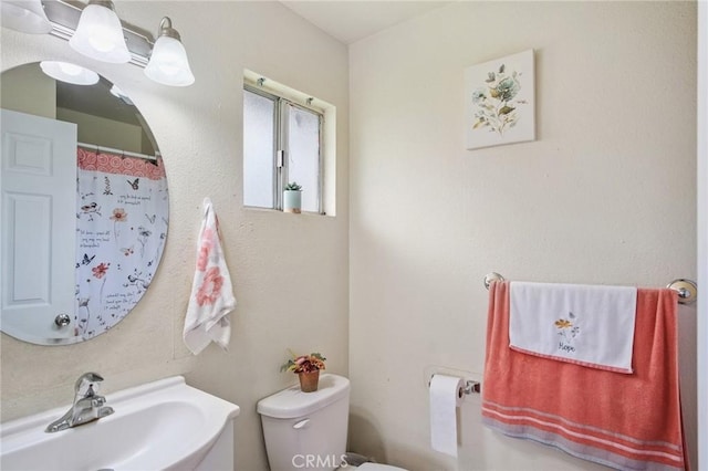 bathroom with a shower with curtain, toilet, and a sink