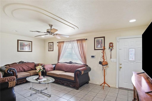 living area with light tile patterned floors, a ceiling fan, baseboards, a textured ceiling, and crown molding