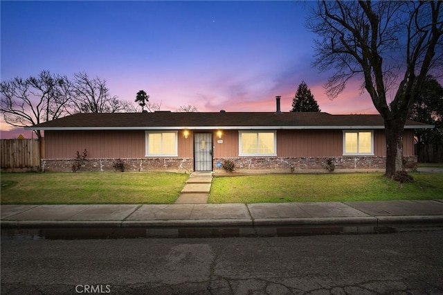 single story home featuring brick siding, a front lawn, and fence