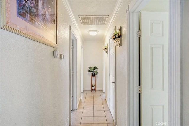 hall with visible vents, ornamental molding, light tile patterned flooring, and a textured wall