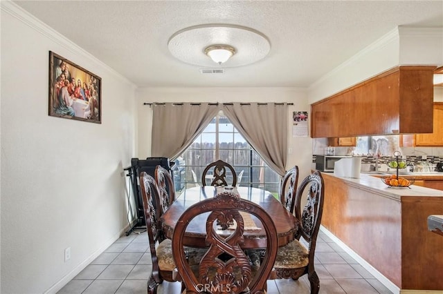 dining space with light tile patterned floors, visible vents, a textured ceiling, and ornamental molding