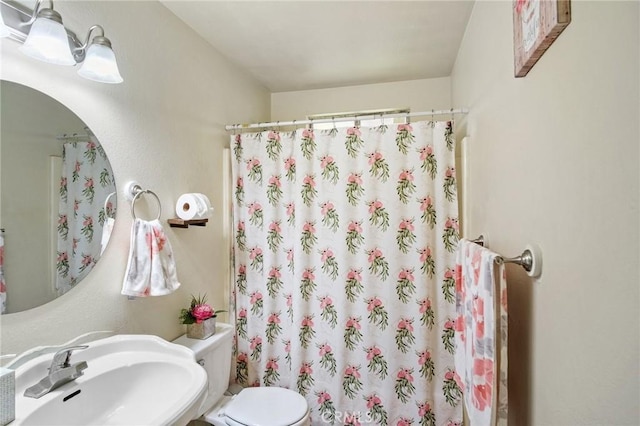 bathroom with a sink, curtained shower, and toilet