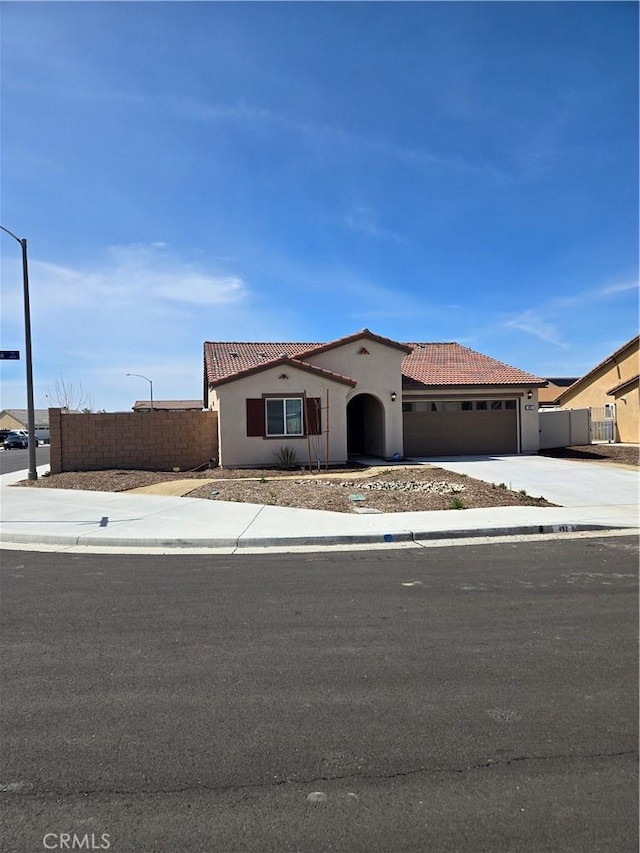 view of front of house featuring a tiled roof, an attached garage, fence, and stucco siding