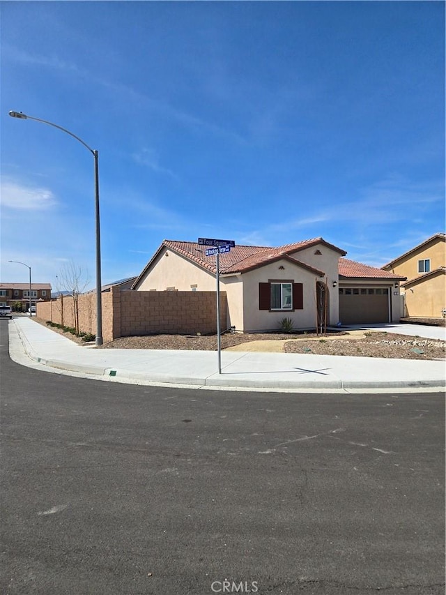 view of front of home with fence, an attached garage, stucco siding, concrete driveway, and a tile roof