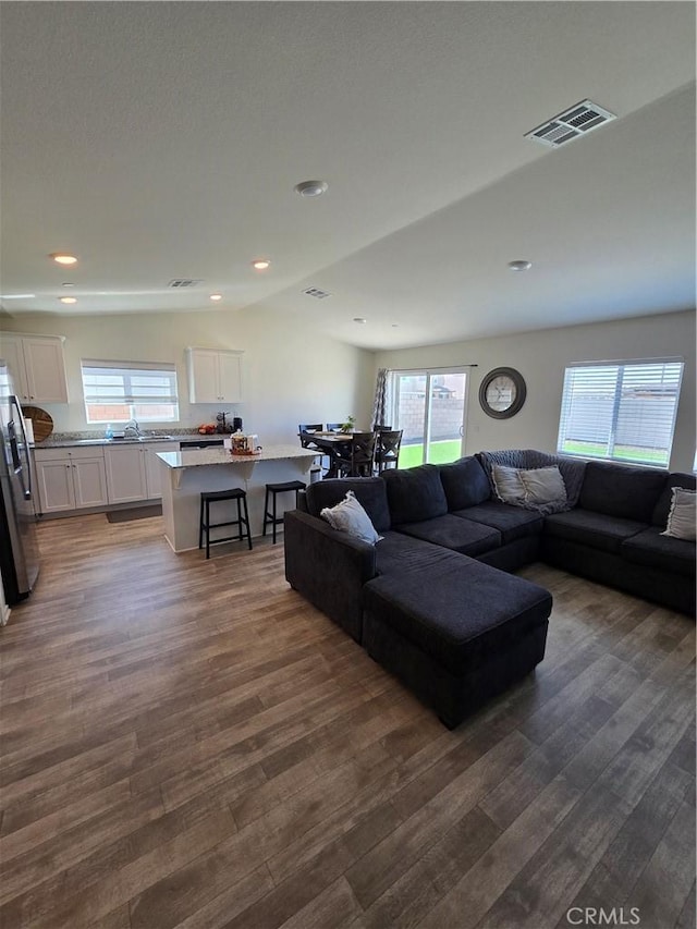 living area featuring dark wood finished floors, visible vents, recessed lighting, and vaulted ceiling