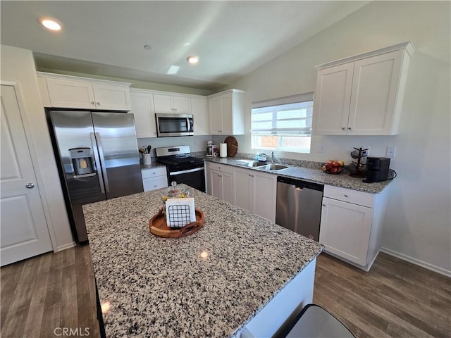 kitchen with a sink, dark wood-style floors, appliances with stainless steel finishes, white cabinets, and lofted ceiling