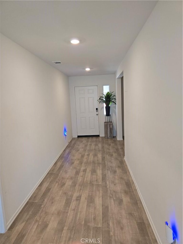 corridor with visible vents, baseboards, and wood finished floors