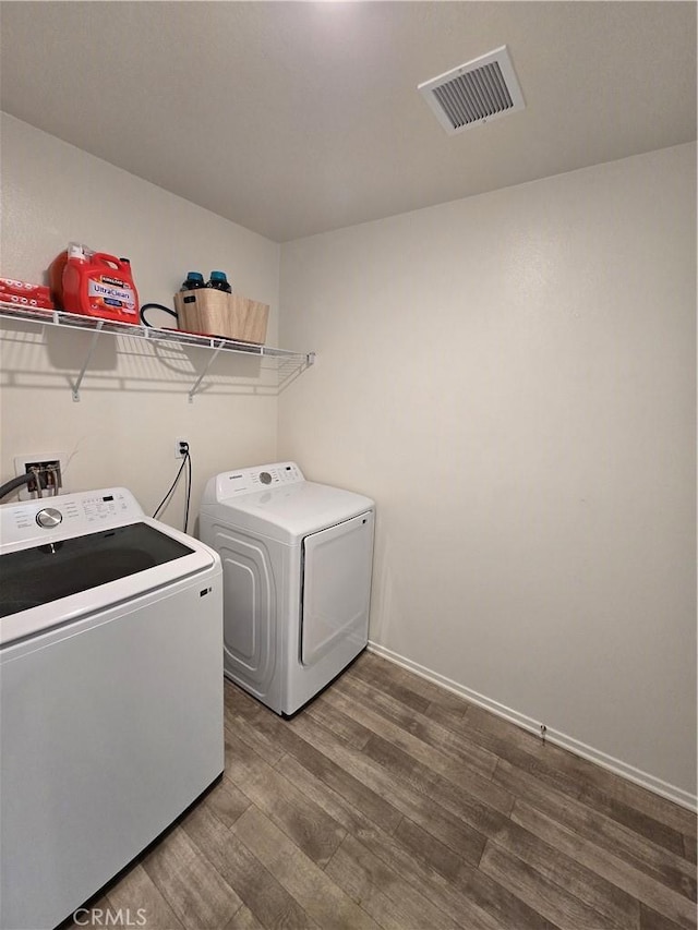 laundry room with visible vents, washer and clothes dryer, wood finished floors, baseboards, and laundry area