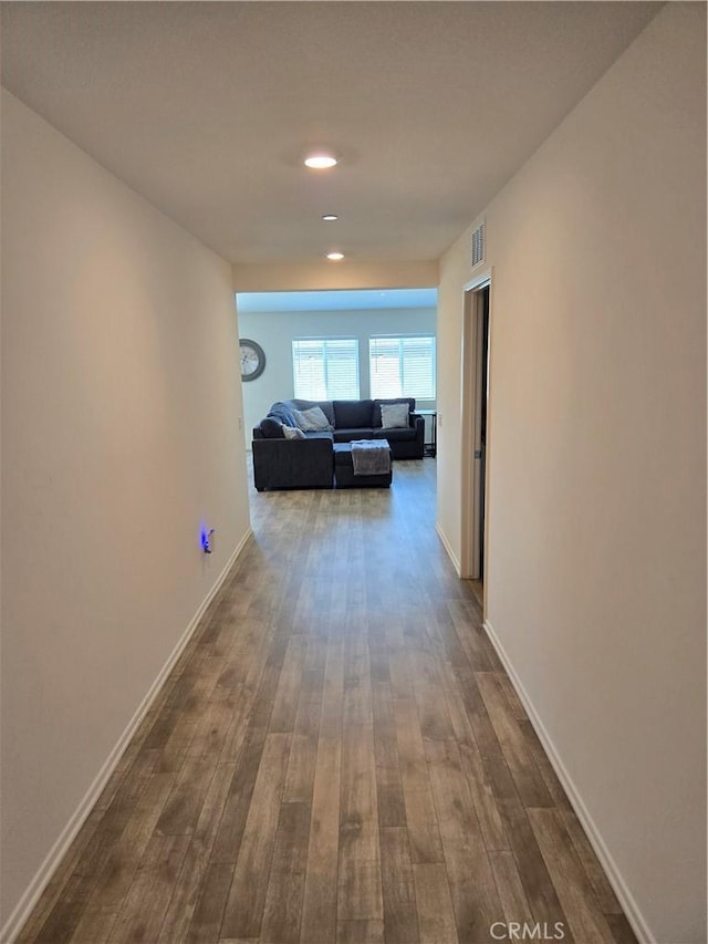 hallway with visible vents, baseboards, and dark wood-style flooring