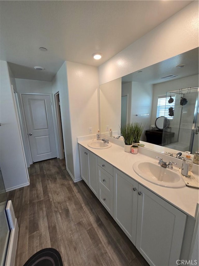 full bathroom with a shower stall, wood finished floors, double vanity, and a sink