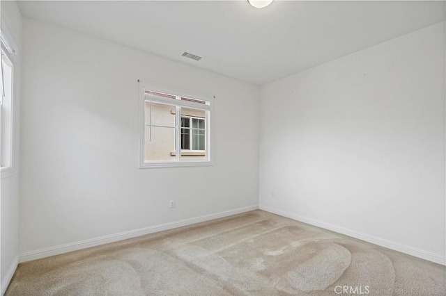 carpeted empty room featuring baseboards and visible vents