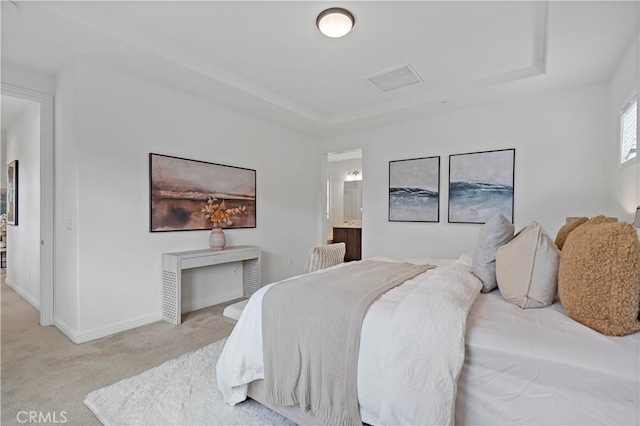 bedroom with light colored carpet, baseboards, a raised ceiling, ensuite bath, and visible vents