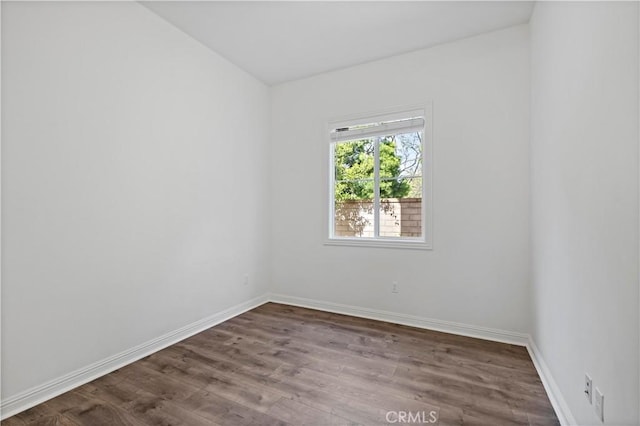 unfurnished room featuring baseboards and dark wood-style flooring