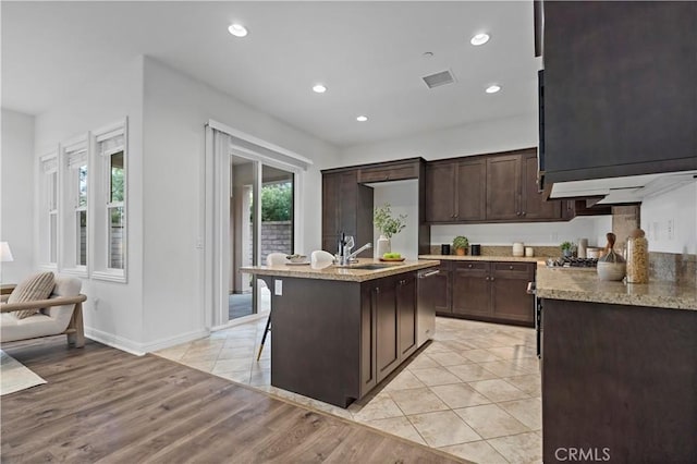 kitchen featuring visible vents, a sink, dark brown cabinets, and plenty of natural light