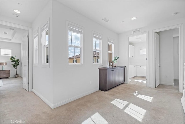 hall with light colored carpet, visible vents, and baseboards
